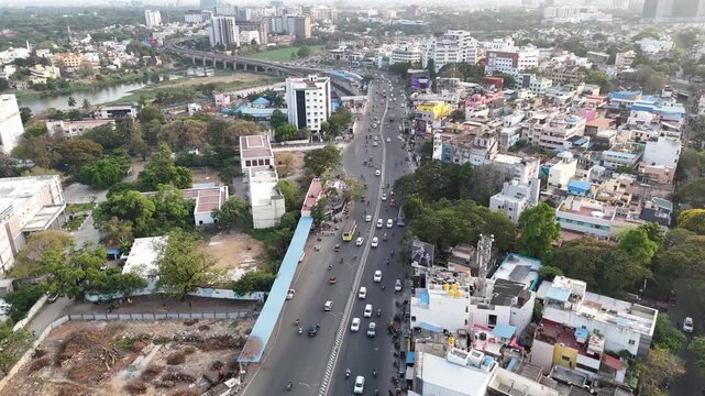 An aerial view of Chennai's Guindy showcases complex elevated roads and a metro line. Modern high-rises contrasting with the river on the left, highlighting a bustling transport and business hub.