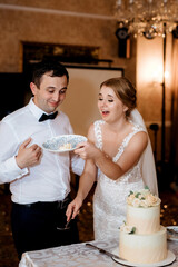 newlyweds happily cut and taste the wedding cake