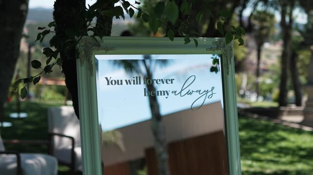 Mirror wedding sign with love quote displayed in outdoor garden
