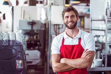 Fototapeta premium Man in late twenties in red apron, white polo making coffee at cafe using espresso machine