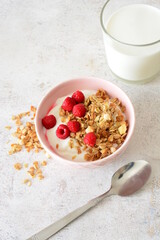 Healthy breakfast Yogurt with granola, raspberries and a glass of milk vertical photo