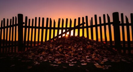 Obraz premium An autumn pile of dry leaves silhouetted against a beautiful golden sunset, casting a tranquil and moody atmosphere in the garden
