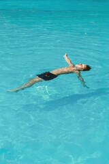 Boy Floating Relaxed in Blue Swimming Pool on Summer Day