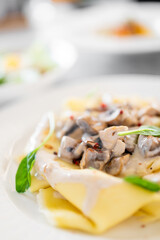 Close-up of creamy mushroom pasta with herbs and pepper flakes, served on a white plate. Gourmet vegetarian dish, ideal for restaurant, cookbook, or food blog use