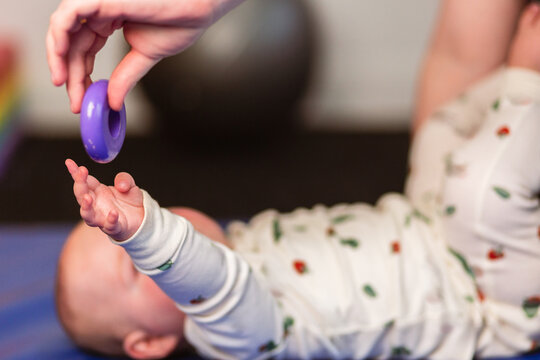 Baby on mat reaching for toy during head turning or neck ROM activity -for torticollis