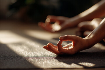 Peaceful yoga scene with hands in Gyan mudra pose, lit by warm natural sunlight