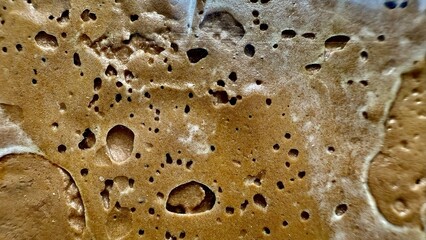 abstract texture of rough brown surface with dark holes and bubbles for commercial or editorial use