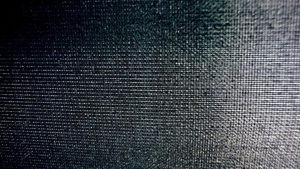 dark metallic mesh texture with reflective grid pattern illuminated by moody light for abstract...