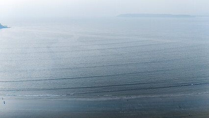 Aerial shot of Caranzalem Beach in Goa after sunset during winter, with mist over the Arabian Sea and calm waters creating a serene coastal view.