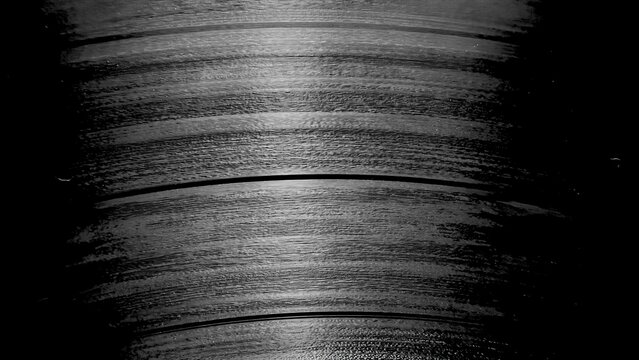 textured close up of vintage vinyl record grooves in dramatic black and white lighting for abstract wallpaper or editorial background