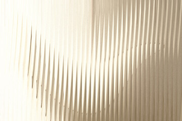 A closeup view of textured glass with vertical ridges, illuminated by soft light creating a subtle gradient effect