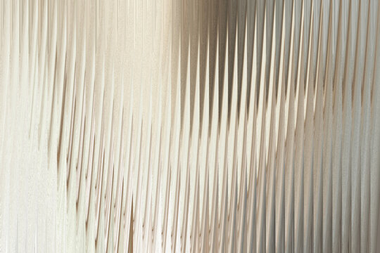 A closeup shot of a textured surface with vertical, wavy ridges and a subtle shimmering effect, creating an abstract and elegant background