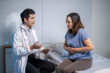 Obraz premium Doctor visiting patient suffering from abdominal pain in hospital room