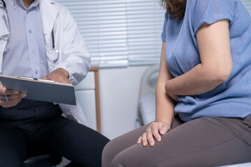 Obraz premium Doctor taking notes while patient suffering abdominal pain in hospital