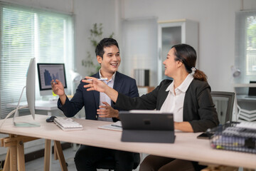 Asian businesspeople discussing work using computer and tablet in office