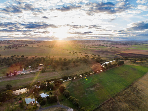 Sunlight streaming over river running through farmland in the Hunter region of New South Wales