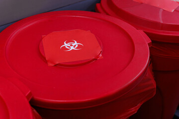 Medical waste disposal room with red biohazard containers and bins