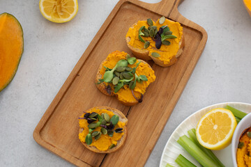 Healthy autumn snack with pumpkin spread and seed topping on wooden board. Pumpkin hummus