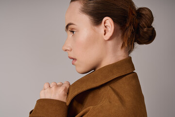 Fashionable young woman showcases modern style in chic brown jacket and elegant profile shot
