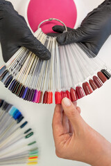 A hand holds a fan of nail polish colors, showcasing a diverse range of shades for manicure selection in a salon