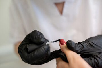 A nail technician holding a brush and preparing to apply gel polish on a clients nails, demonstrating expertise in nail artistry