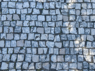 Cobbled stone surface with paving pattern. Textured ground and roadway material creating historic