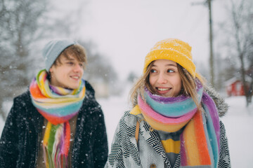 Happy Young Couple Walking in the Snow, Wearing Colorful Winter Coats and Scarves, Soft Overcast Light, Candid Photography Style, Winter Lifestyle and Seasonal Joy