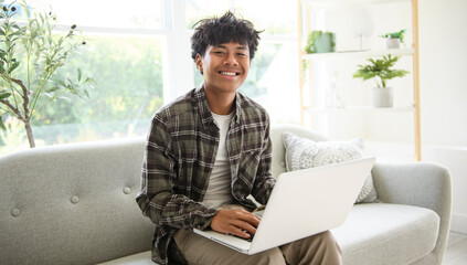 Fototapeta premium thai teen using laptop at home sofa