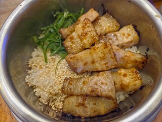 Samgyeopsal Sotbap, a Korean dish of rice cooked in a metal pot with grilled Korean pork belly.