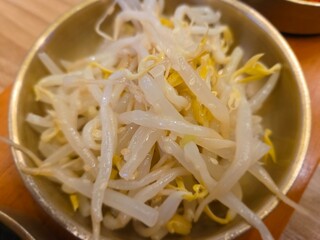 close-up, metal bowl filled with a side dish of stir-fried or seasoned bean sprouts. 