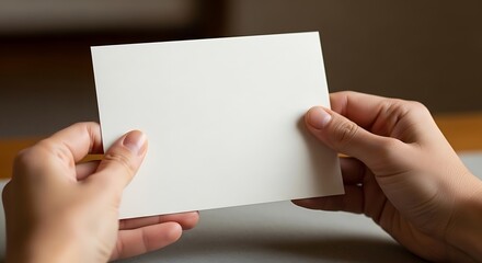 Obraz premium Hands delicately present a pristine, blank card or invitation sheet