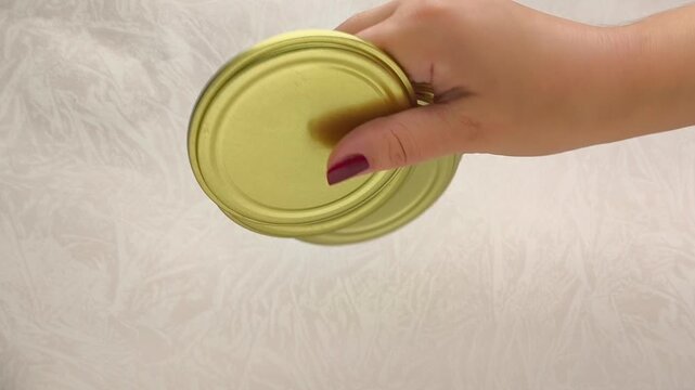 A gold metal lid for swirling cans in a woman's hand. the key for turning cans