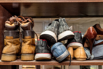 old shoes in the shoemaker's repair shop. A close-up of various stylish shoes on a shelf, featuring high heels, sneakers, and boots, capturing a fashionable display