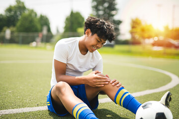 nice Boy with soccer ball outside on field having injury