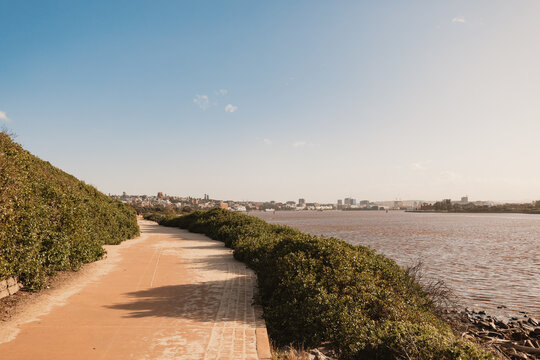 Aftermath of flooding in Newcastle with sand over breakwater path and dirty water in the Hunter Rive
