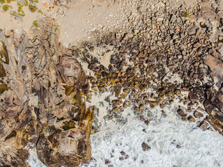 A top down aerial view of a rocky cliff meeting a pebble beach The Beauty of a Coastal Geology
