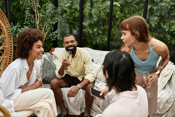 Joyful gathering of stylish young friends enjoying laughter at an outdoor cafe on a sunny day