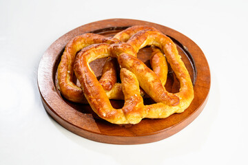 Closeup view of a pretzel loaf on a wooden tray in a white table background. Concept of Oktoberfest. Bavarian German culture festival decoration symbol