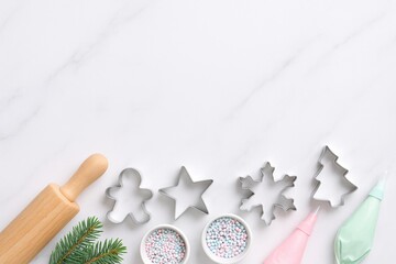 christmas baking preparation with cookie cutters, sprinkles, and icing on marble background