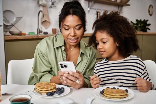 Mom and daughter enjoy a cozy breakfast while sharing moments at home - Powered by Adobe
