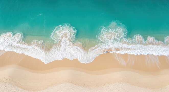 An aerial view of turquoise ocean waves gently crashing onto a pristine sandy