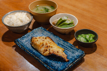 Traditional Japanese dinner with grilled fish, rice, miso soup and side dishes
