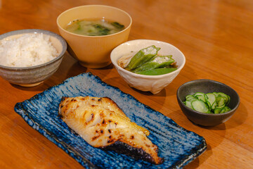 Traditional Japanese dinner with grilled fish, rice, miso soup and side dishes
