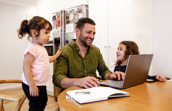 Father and daughters using laptop on dining table