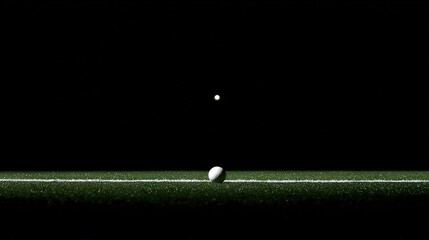 A golf ball prepared for a shot on a green surface, lit dramatically against a dark background, perfect for sports articles, promotional material, or motivational content related to golf and practice