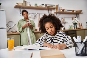 Mother supports daughter with homework in their cozy kitchen at home