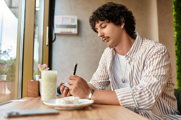 Charming young man enjoying a moment of creativity in a cozy cafe on a sunny afternoon