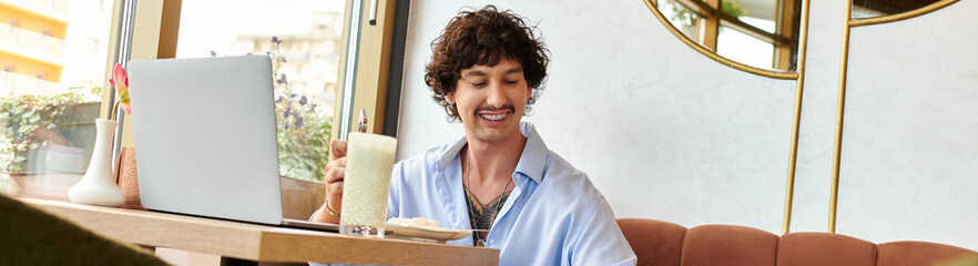 Handsome young man enjoying a refreshing drink in a cozy indoor cafe setting