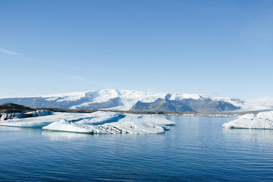 J&ouml;kuls&aacute;rl&oacute;n lagoon. Tranquil landscape of glacier lagoon on a sunny day: calm crystal-clear lake with large chunks of ice sparkling in the sun and high mountains covered with snow in the background.
