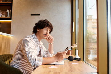 Young man enjoys a moment of reflection in a cozy cafe filled with warmth and creativity © Bliss